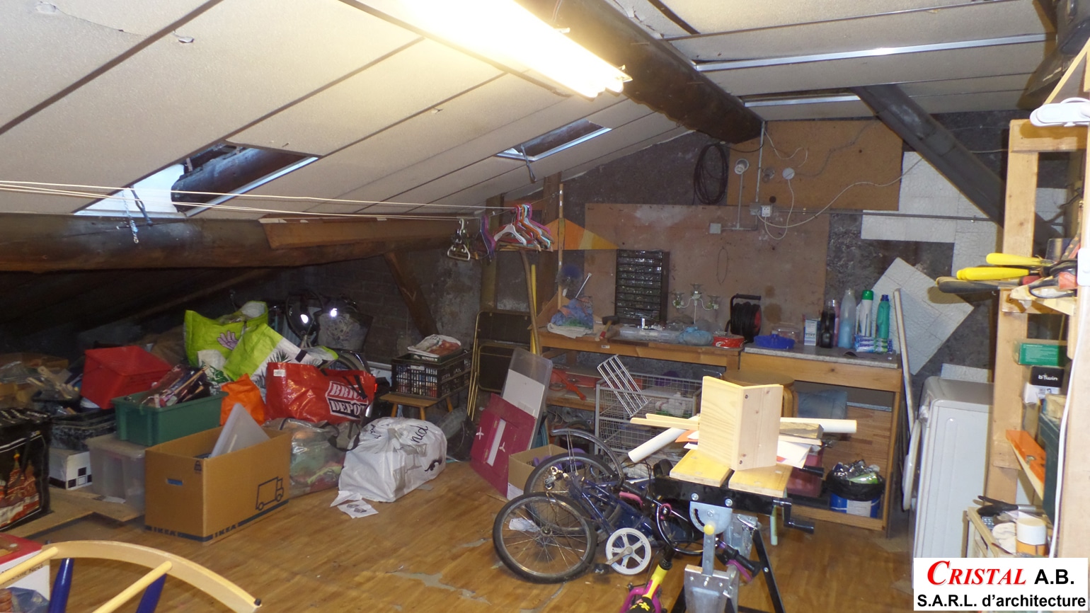 Grenier encombré avec cartons IKEA, sacs Brico Depot, vélo et établi de bricolage. CRISTAL A.B. S.A.R.L. d'architecture.