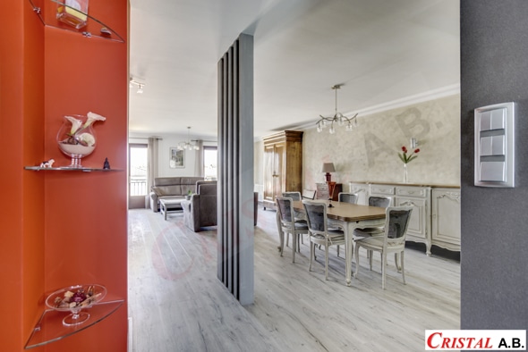 Intérieur moderne Cristal AB avec salon, salle à manger classique, parquet clair et niche murale orange décorative.