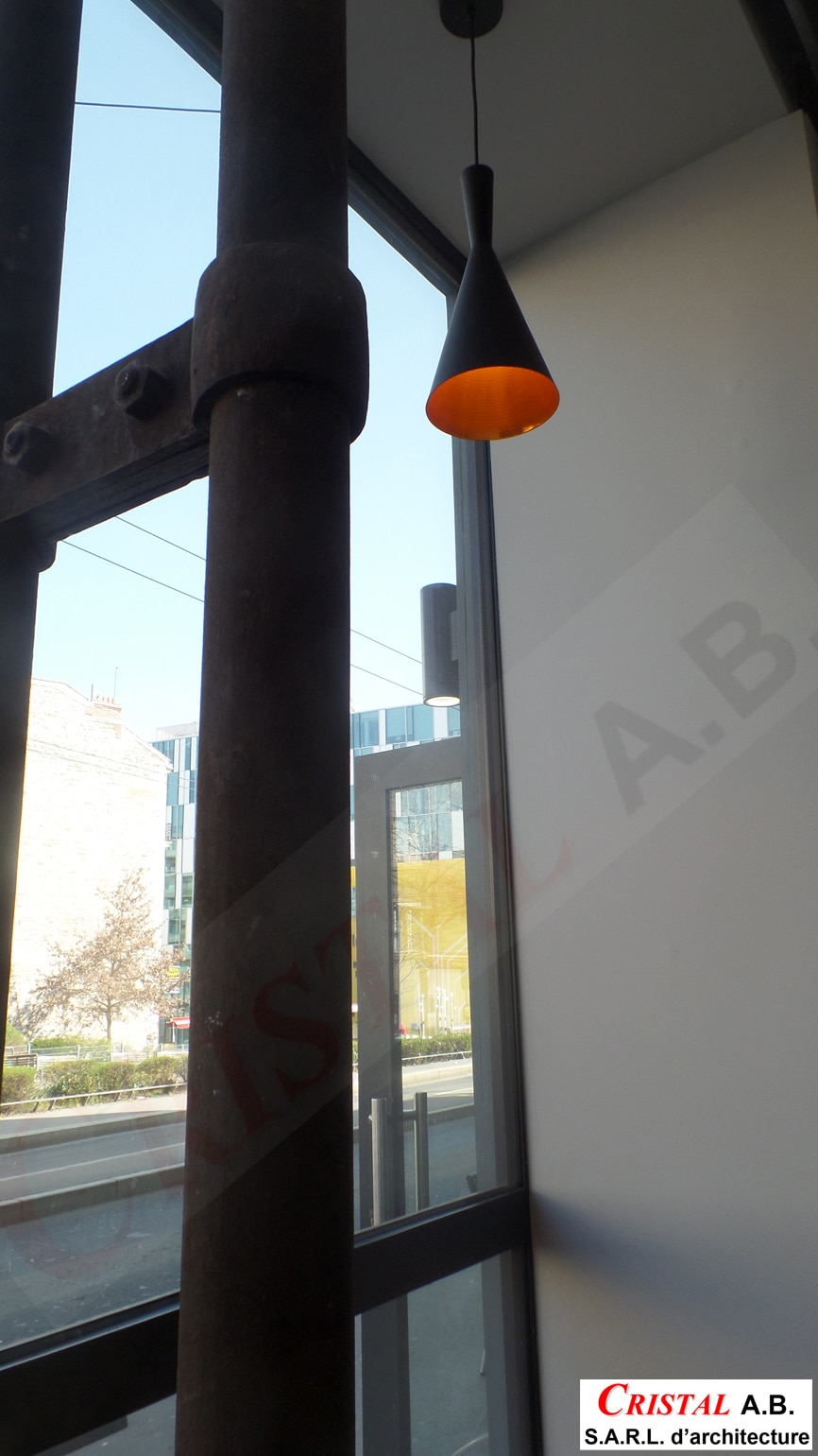 Colonne métallique, luminaire design orange et vue urbaine. Logo Cristal A.B. S.A.R.L. d'architecture.