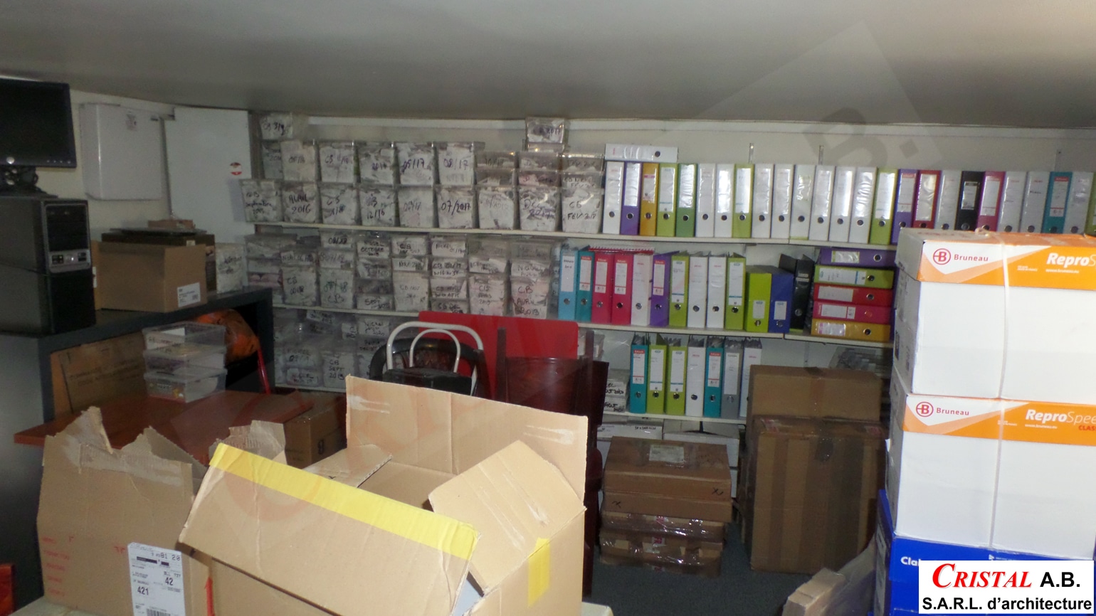 Salle d'archives d'architecture CRISTAL A.B. avec étagères de classeurs colorés et boîtes de rangement.