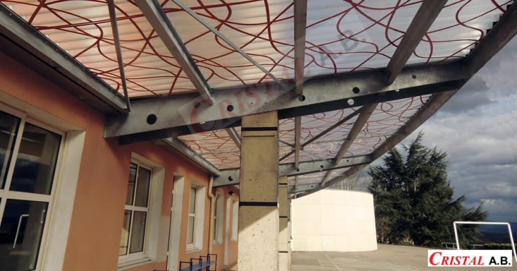 Auvent Cristal A.B. : Structure Métal et Toit Translucide Auvent Cristal A.B. avec structure métallique et toit translucide à motifs rouges sur un bâtiment moderne.