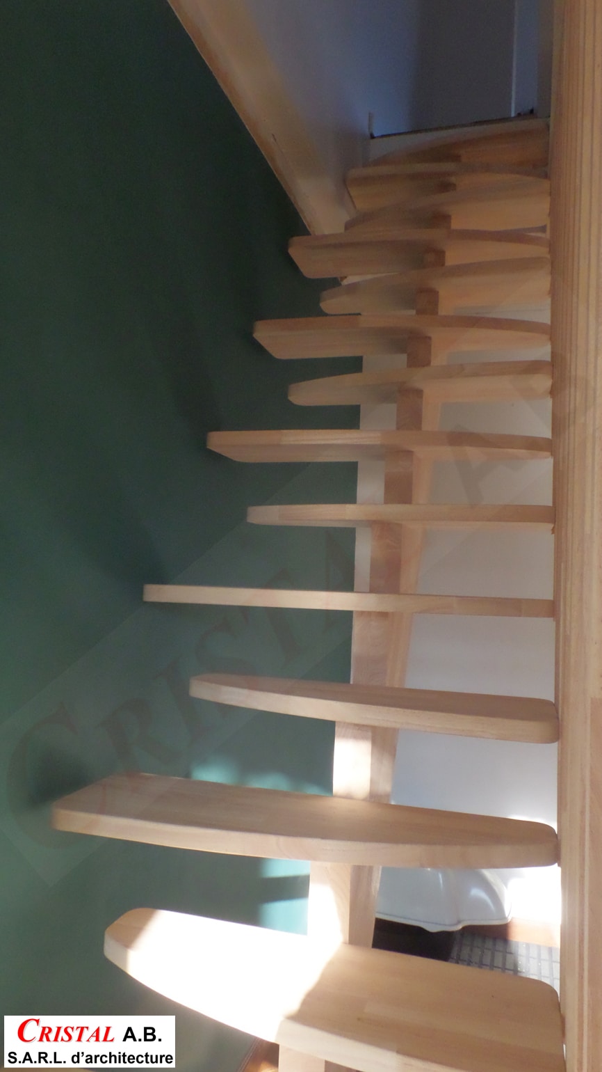 Escalier hélicoïdal en bois clair, design gain de place par Cristal A.B. Architecture, mur vert foncé.
