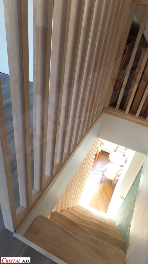 Escalier en bois avec garde-corps à claire-voie et marches claires, vue de dessus. Cristal A.B.