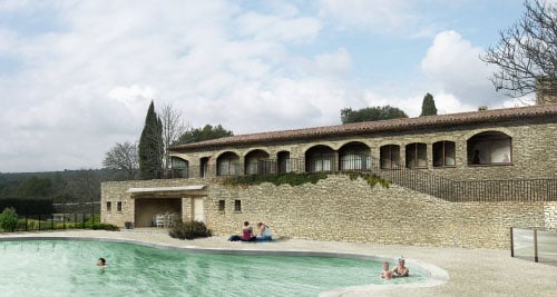 Villa en pierre avec piscine turquoise et vacanciers se baignant en Provence sous un ciel voilé.