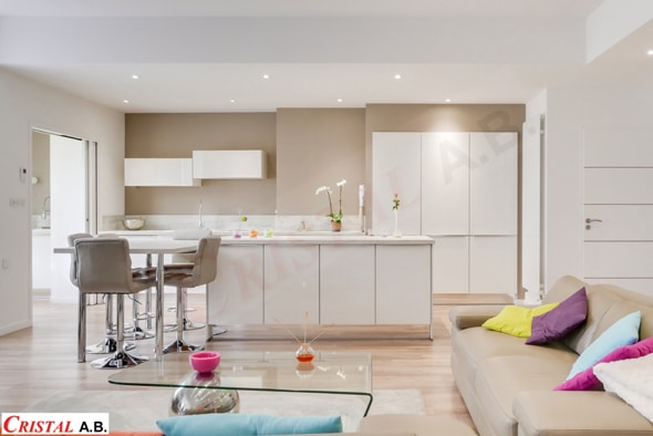 Cuisine moderne blanche avec îlot et salon lumineux Cristal A.B. Décoration contemporaine et épurée.