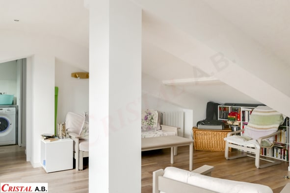 Salon sous combles lumineux avec mobilier clair et parquet. Logo Cristal A.B. en bas à gauche.